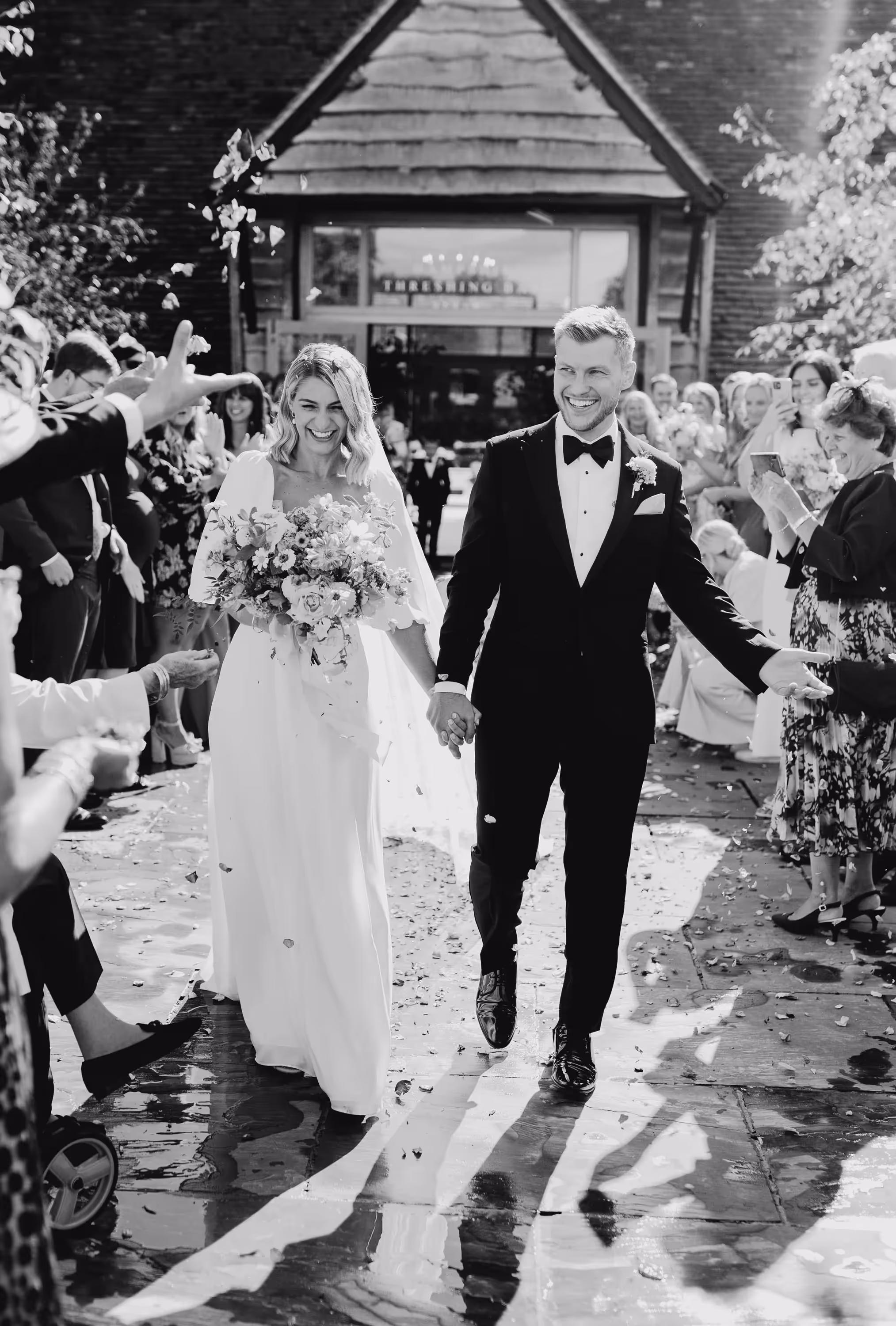 black and white photograph of bride and groom being showered with confetti