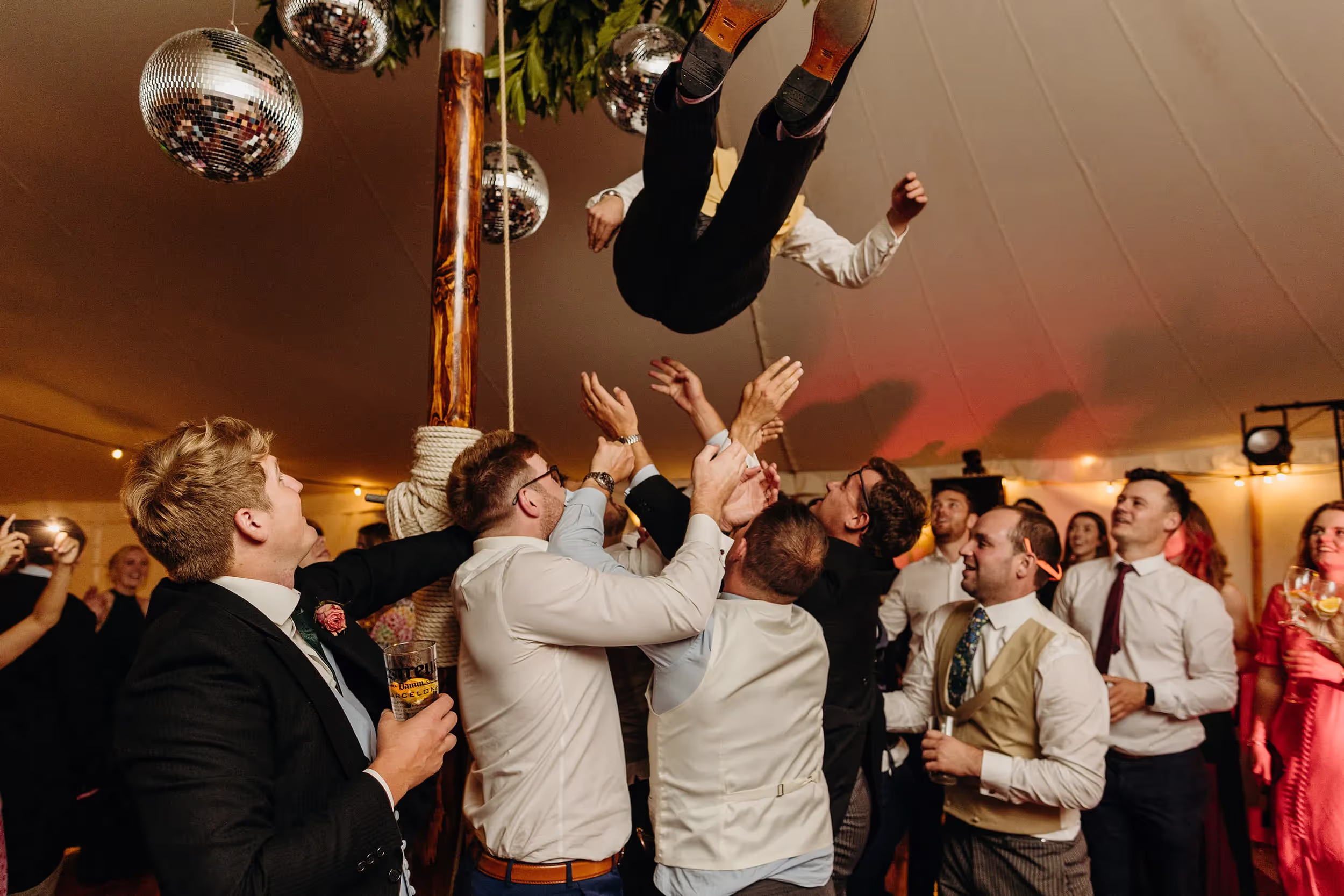 groom being thrown up in the air on dancefloor
