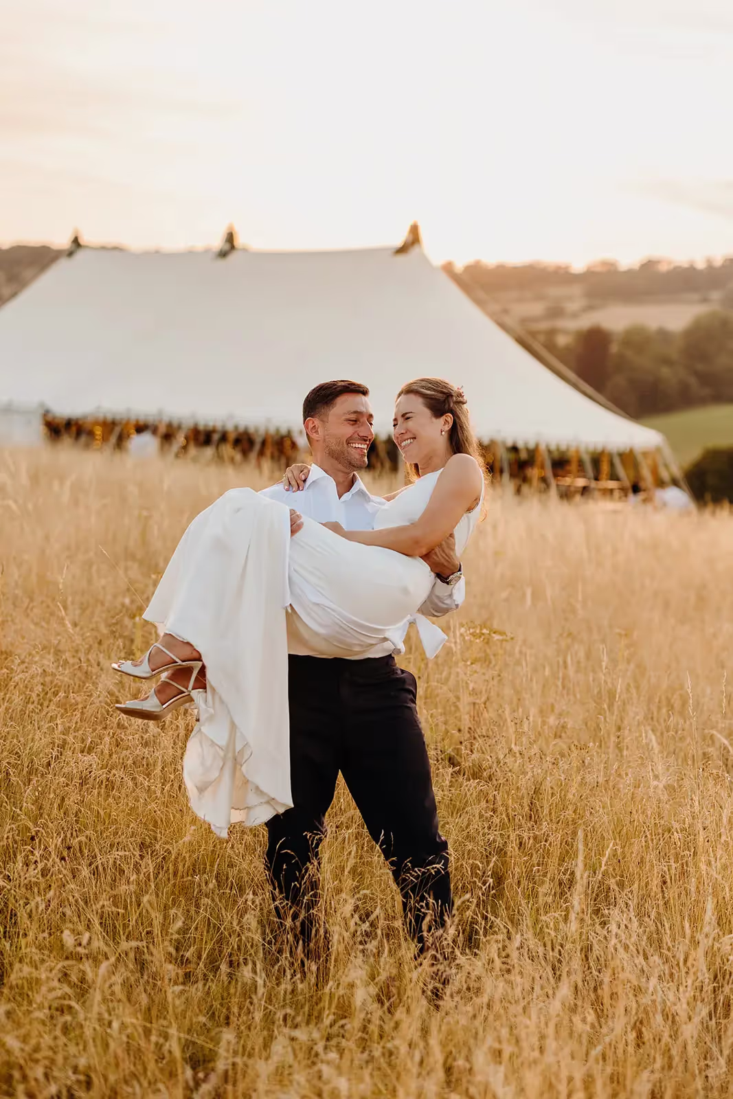 Groom picks bride up during portrait session at marquee wedding in Wiltshire