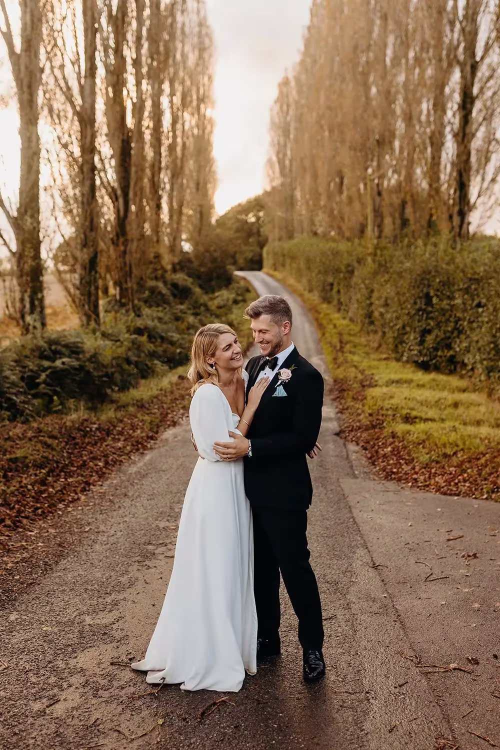 Bride and groom embrace down pine street at wedding in Hampshire