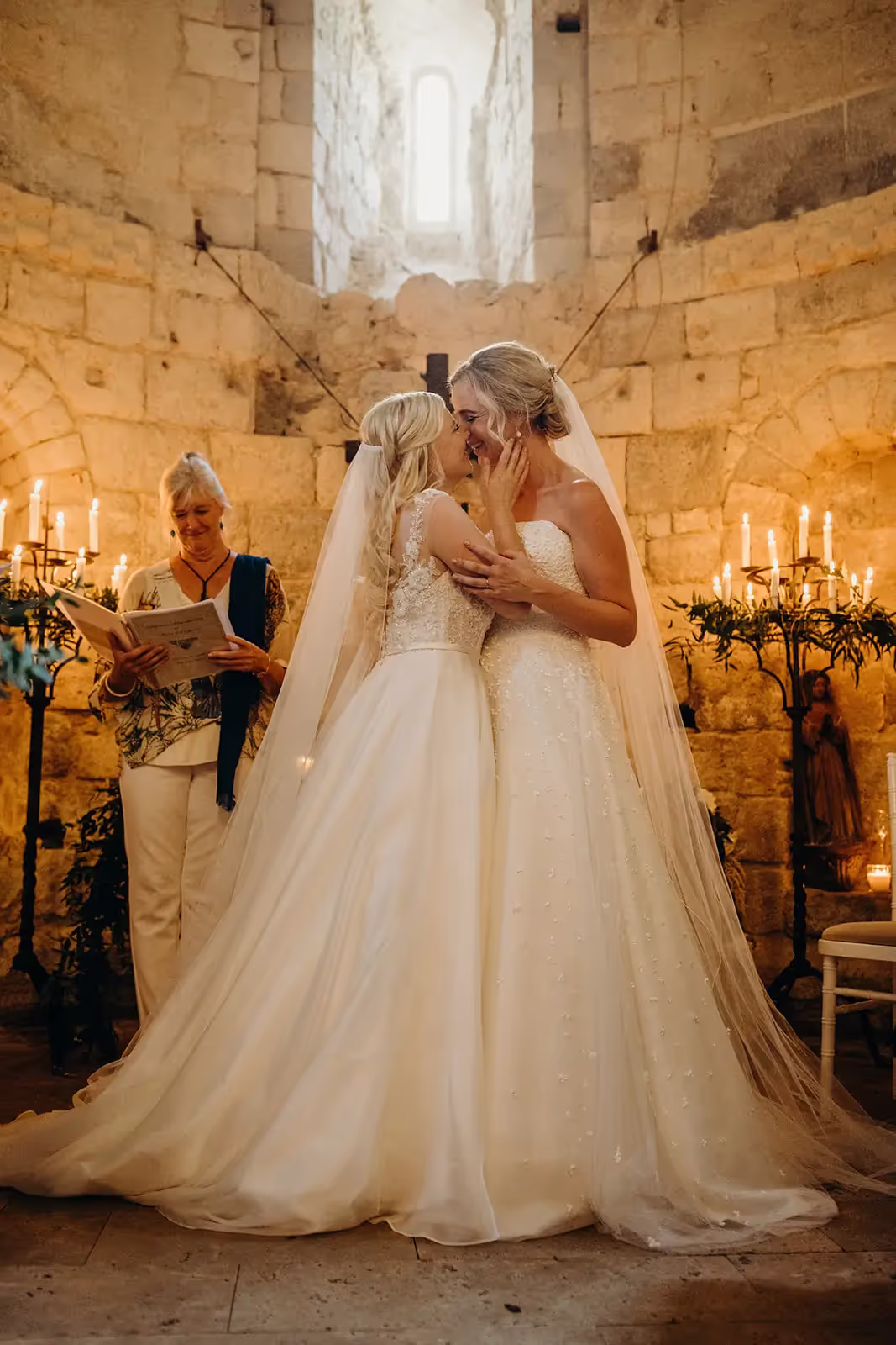 Two brides kiss during chapel ceremony at destination wedding in France